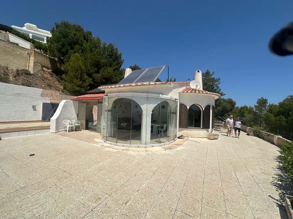 Véranda avec arches en rénovation sur terrain sableux.