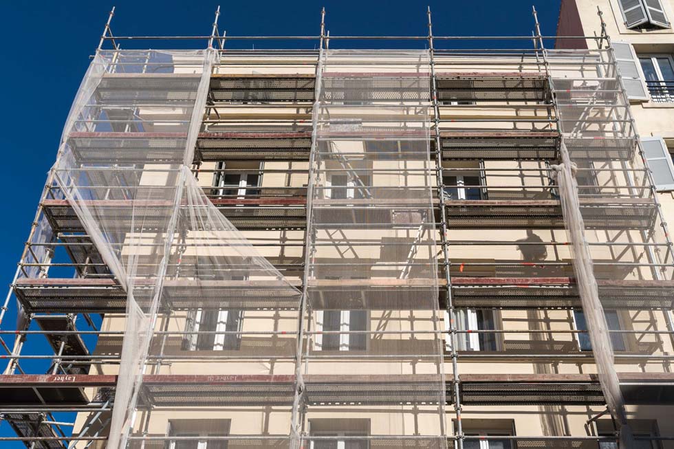 Bâtiment en travaux avec plusieurs niveaux d’échafaudages.
